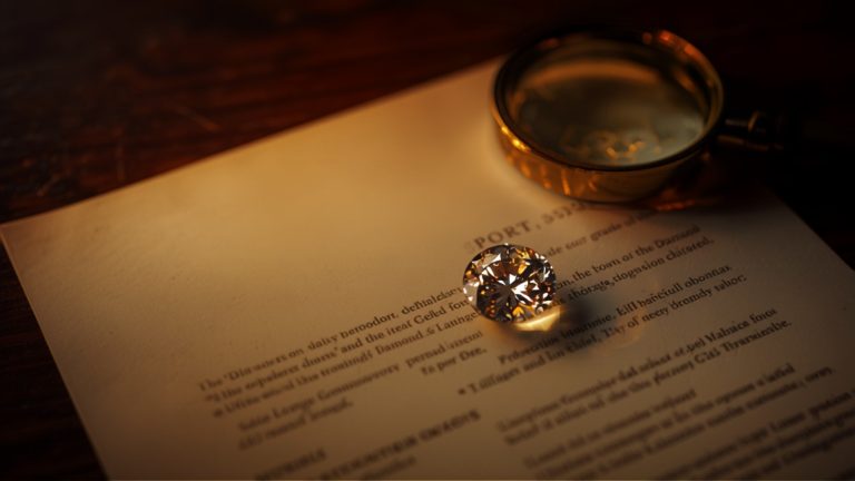 Diamond grading report beside a loose diamond and a jeweler's loupe