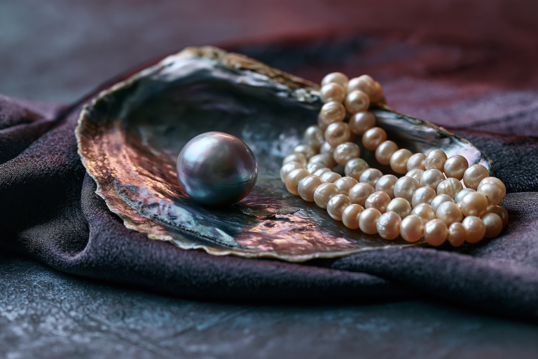 Strand of cultured pearls beside a rare natural pearl